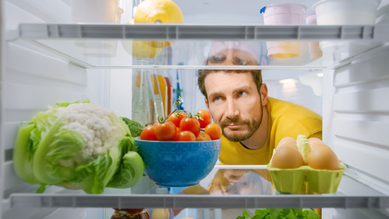 uomo che guarda stupito nel frigorifero