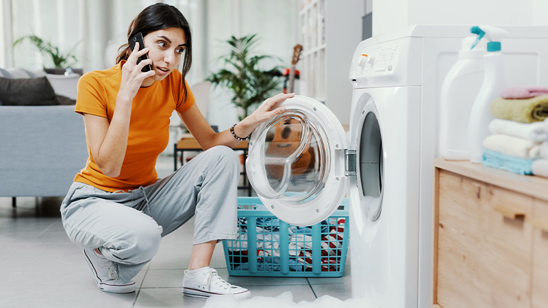 Persona davanti alla lavatrice, al telefono con un tecnico 