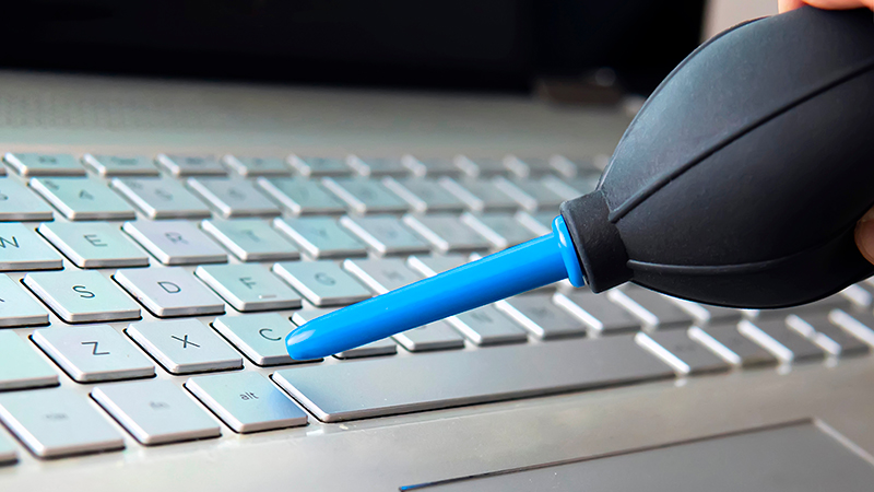 close-up-shot-of-female-hand-sweeping-dust-from-laptop-keyboard-using-picture-id1317036234-800x450